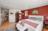 Experience comfort and style in this inviting bedroom, featuring a striking accent wall in a rich, warm hue.