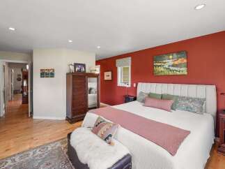 Experience comfort and style in this inviting bedroom, featuring a striking accent wall in a rich, warm hue.