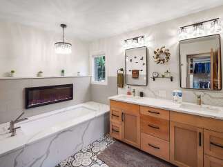 Experience ultimate relaxation in this luxurious bathroom featuring a deep soaking tub with a modern electric fireplace for a cozy ambiance.