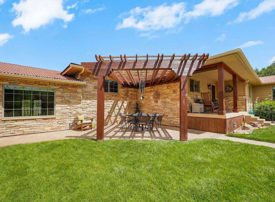 Enjoy outdoor living with this charming patio featuring a wooden pergola, perfect for al fresco dining under the sun or stars.