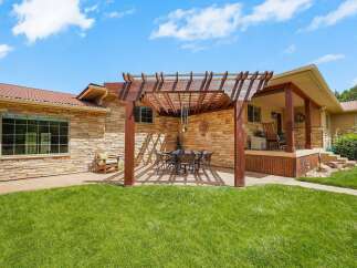 Enjoy outdoor living with this charming patio featuring a wooden pergola, perfect for al fresco dining under the sun or stars.