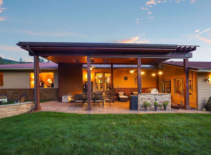 Enjoy outdoor living at its finest with this expansive covered patio, complete with a built-in stone grill and ample seating.