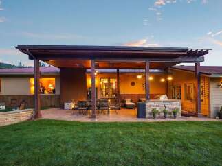 Enjoy outdoor living at its finest with this expansive covered patio, complete with a built-in stone grill and ample seating.