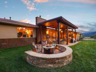 Experience ultimate outdoor living with this stunning backyard oasis, featuring a curved stone fire pit area perfect for cozy evenings.