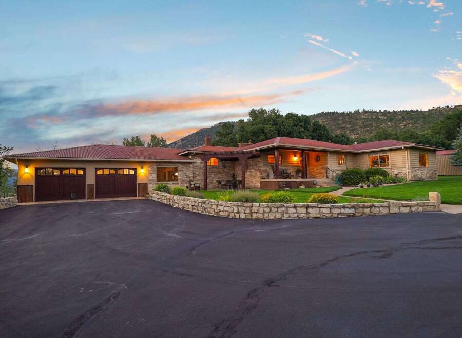 Experience serene country living in this charming ranch-style home, featuring a welcoming stone facade and a spacious attached garage.