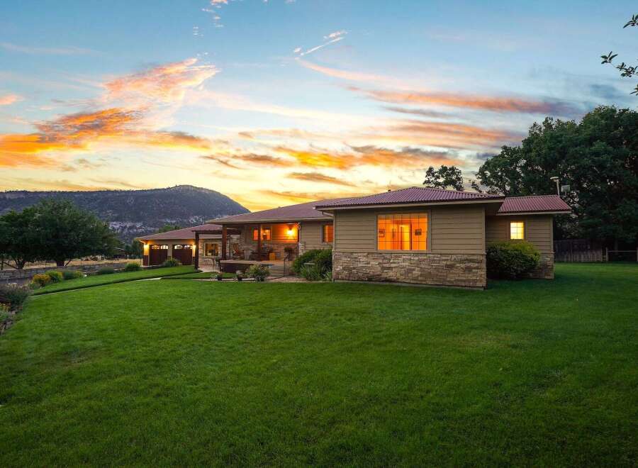 Experience serene living in this charming home, nestled against a majestic mountain backdrop under a vibrant sunset sky.