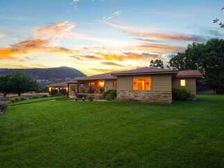 Experience serene living in this charming home, nestled against a majestic mountain backdrop under a vibrant sunset sky.