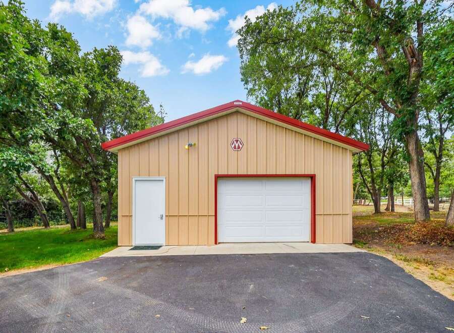 Discover this versatile metal building, perfect for storage or a workshop, featuring a spacious garage door and a convenient side entrance.