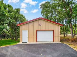 Discover this versatile metal building, perfect for storage or a workshop, featuring a spacious garage door and a convenient side entrance.
