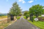 Welcome to Rudolph Farms, a stunning property offering a picturesque setting with a long, paved driveway leading through elegant black gates.