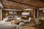 Experience luxurious mountain living in this stunning open-concept living space, featuring a modern sectional sofa, a sleek kitchen island, and a rustic wooden ceiling.