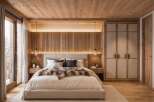 Experience rustic luxury in this stunning bedroom, featuring a cozy king-sized bed adorned with a plush fur throw and a textured headboard.