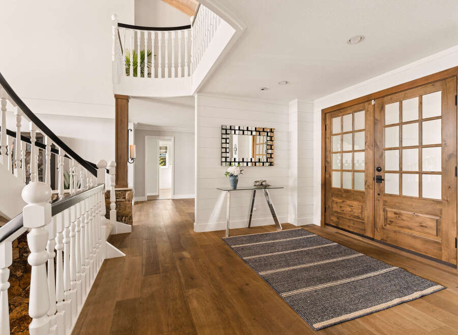 Step into this grand foyer featuring a sweeping staircase with a black handrail and white balusters, complemented by natural stone accents.