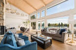 Experience luxurious waterfront living in this stunning home featuring a vaulted wood-beamed ceiling and expansive windows that flood the space with natural light.