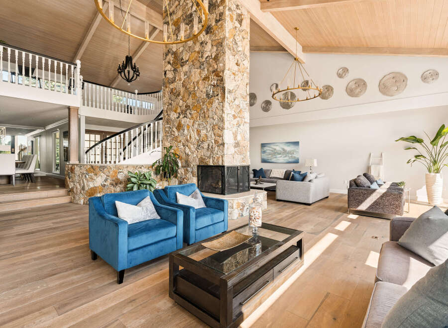 Experience luxurious living in this grand living room, featuring a striking stone fireplace as the centerpiece.