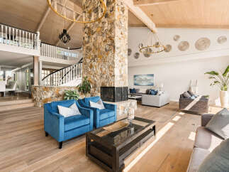 Experience luxurious living in this grand living room, featuring a striking stone fireplace as the centerpiece.