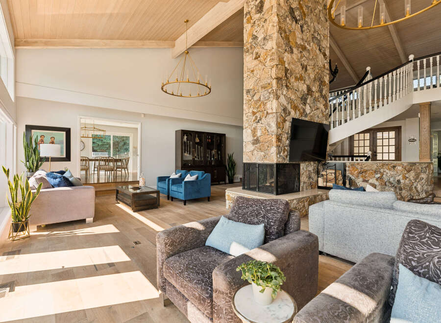 Experience luxurious living in this spacious great room, featuring a stunning floor-to-ceiling stone fireplace and a grand spiral staircase.