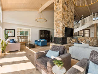 Experience luxurious living in this spacious great room, featuring a stunning floor-to-ceiling stone fireplace and a grand spiral staircase.