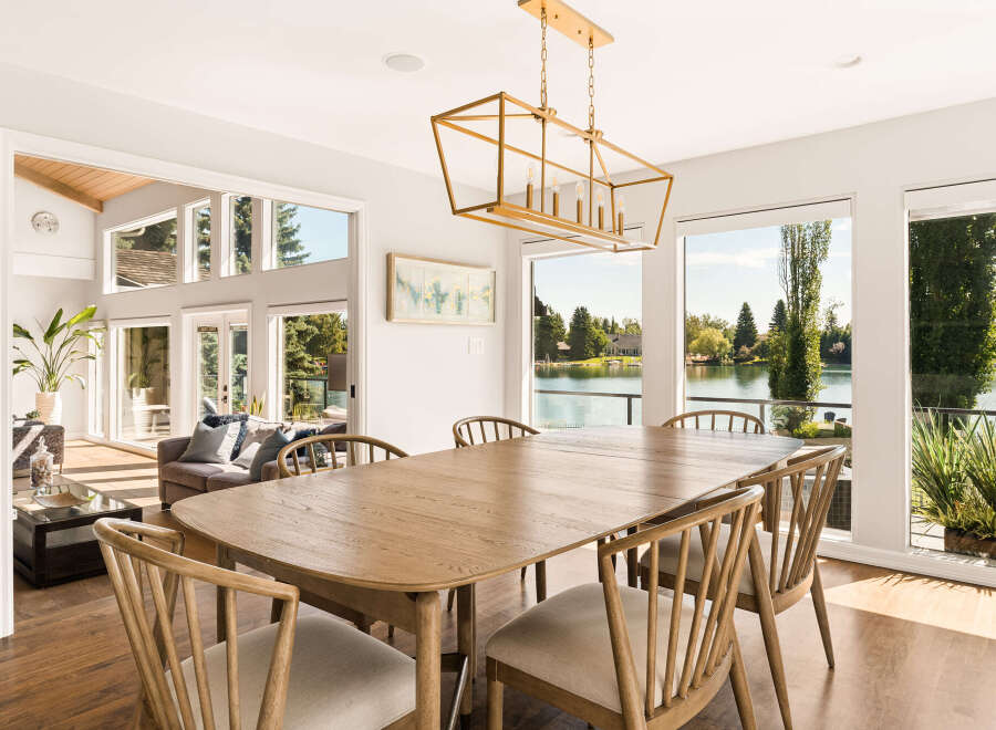 Experience elegant dining with this spacious wooden table and chairs, perfectly situated to capture breathtaking lake views through expansive windows.