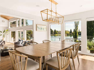Experience elegant dining with this spacious wooden table and chairs, perfectly situated to capture breathtaking lake views through expansive windows.