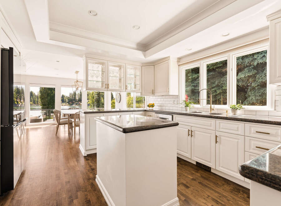 Experience luxury living in this stunning kitchen featuring pristine white cabinetry, elegant granite countertops, and a spacious island perfect for entertaining.