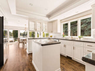 Experience luxury living in this stunning kitchen featuring pristine white cabinetry, elegant granite countertops, and a spacious island perfect for entertaining.