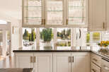 Experience breathtaking lake views from this stunning kitchen, featuring elegant glass-front cabinetry filled with glassware.