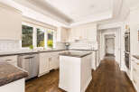This stunning kitchen boasts elegant cream cabinetry with gold hardware, complemented by a classic subway tile backsplash.