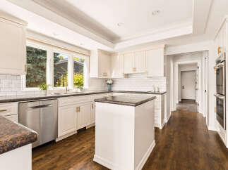 This stunning kitchen boasts elegant cream cabinetry with gold hardware, complemented by a classic subway tile backsplash.