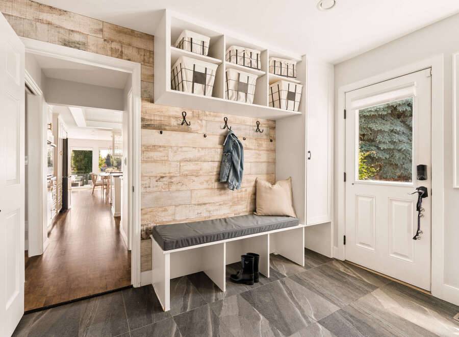 Step into this inviting entryway featuring a stylish built-in bench with storage baskets and a denim jacket hanging on a rustic wood-paneled accent wall.
