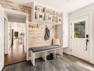 Step into this inviting entryway featuring a stylish built-in bench with storage baskets and a denim jacket hanging on a rustic wood-paneled accent wall.