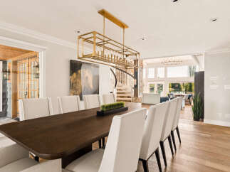 Experience elegant dining in this spacious room, featuring a large, dark wood table surrounded by plush, cream-colored chairs.