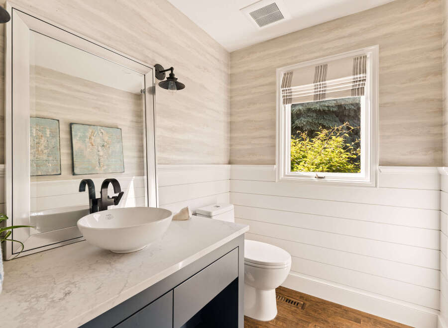 This charming bathroom features a modern vessel sink atop a sleek vanity with a marble countertop.