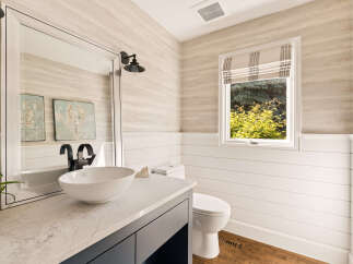 This charming bathroom features a modern vessel sink atop a sleek vanity with a marble countertop.