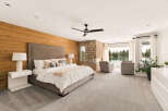 Experience luxury living in this stunning master suite, featuring a king-sized bed with a tufted headboard and a cozy reading nook by the stone fireplace.