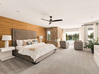Experience luxury living in this stunning master suite, featuring a king-sized bed with a tufted headboard and a cozy reading nook by the stone fireplace.