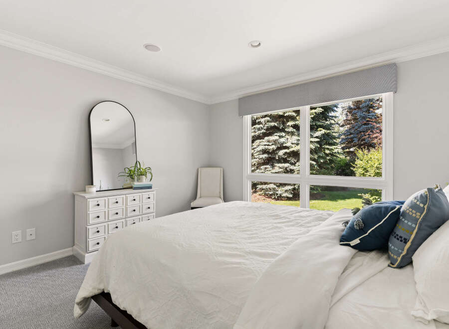 This serene bedroom features a large window offering picturesque views of lush greenery.