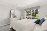 This serene bedroom features a large window offering picturesque views of lush greenery.