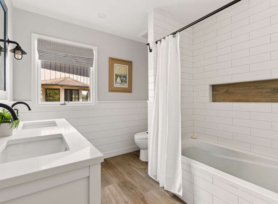 This modern bathroom features a double vanity with sleek black faucets and a white quartz countertop, complemented by shiplap accent walls.