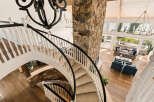 Experience luxury living in this stunning home featuring a grand spiral staircase with a stone accent wall and a dramatic chandelier.