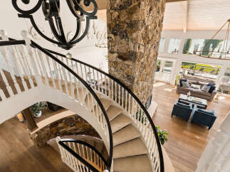 Experience luxury living in this stunning home featuring a grand spiral staircase with a stone accent wall and a dramatic chandelier.