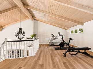 Elevate your fitness routine in this spacious loft gym, featuring a Peloton bike and treadmill.