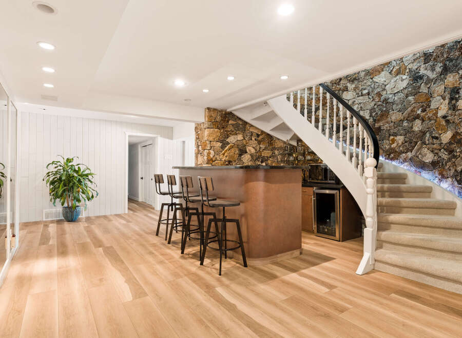 This finished basement features a stylish bar area with four stools, perfect for entertaining guests.