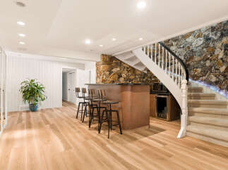 This finished basement features a stylish bar area with four stools, perfect for entertaining guests.