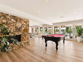 Experience ultimate relaxation and entertainment in this stunning recreational room, featuring a magnificent stone fireplace and a professional-grade pool table.