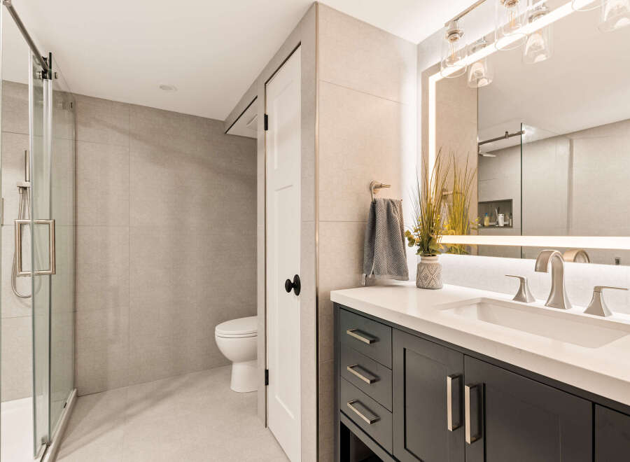 Experience modern luxury in this beautifully appointed bathroom, featuring a sleek glass-enclosed shower and a stylish vanity with a quartz countertop.