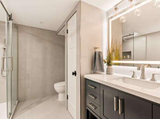 Experience modern luxury in this beautifully appointed bathroom, featuring a sleek glass-enclosed shower and a stylish vanity with a quartz countertop.
