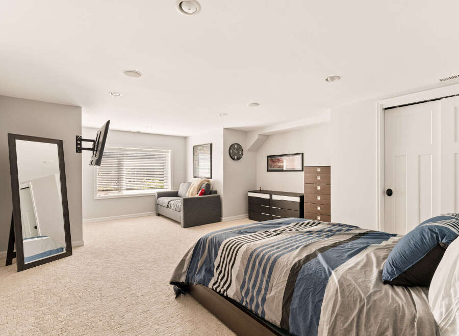 This spacious bedroom features a comfortable king-size bed with a stylish striped comforter, perfect for a restful night's sleep.