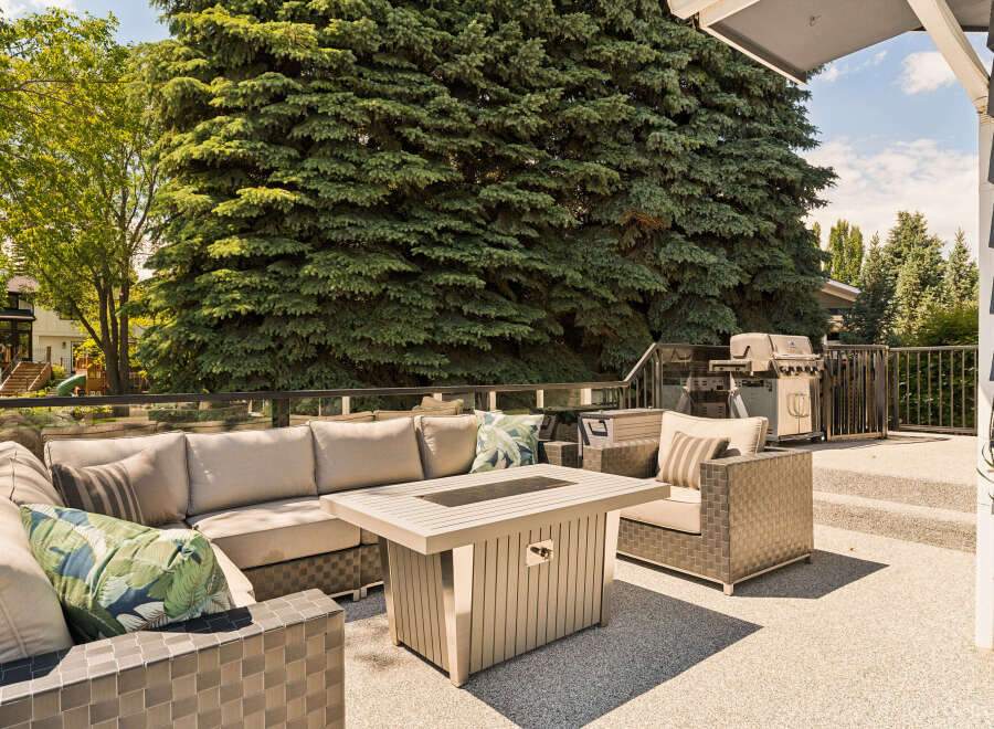 Enjoy outdoor living at its finest on this spacious deck, complete with a comfortable sectional sofa and a modern fire pit table.