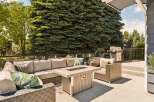 Enjoy outdoor living at its finest on this spacious deck, complete with a comfortable sectional sofa and a modern fire pit table.